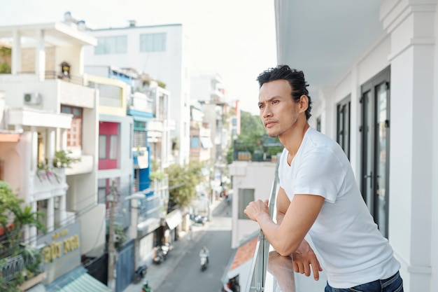 Nadenkend man die op zijn balkon