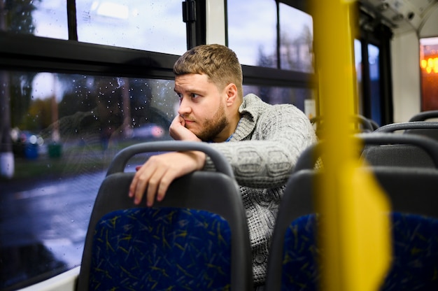 Nadenkend man kijkt uit het raam van de bus