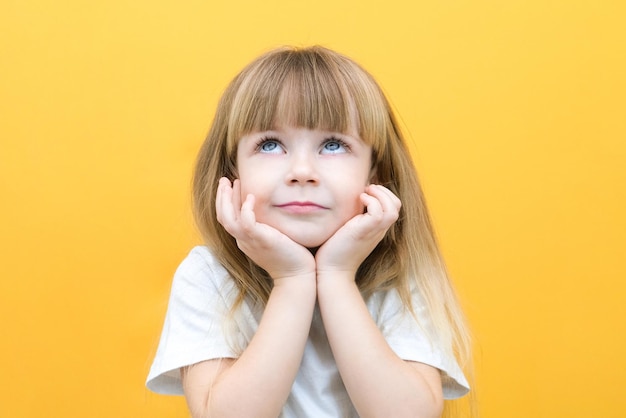 Nadenkend meisje aanraken observatie kin nadenkende schattige dochter die beslissing neemt, verbeeldt gedachte poseren geïsoleerd over gele achtergrond