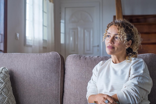 Nadenkend peinzend meisje zit alleen door het raam te kijken denken aan een probleem of reflecterende, angstige melancholische jonge vrouw ernstig gezicht verloren in gedachten voel eenzaam twijfelachtig bezorgd, zijaanzicht