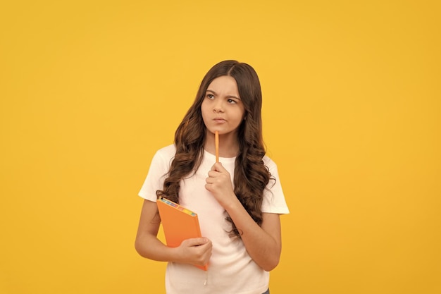 Nadenkend schoolkind klaar om te studeren met werkboek en penschool