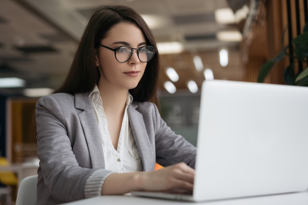 Nadenkend tekstschrijver met behulp van laptop, typen op toetsenbord op kantoor