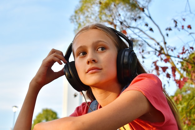 Nadenkend Tienermeisje die in hoofdtelefoons aan muziek luisteren outsite.