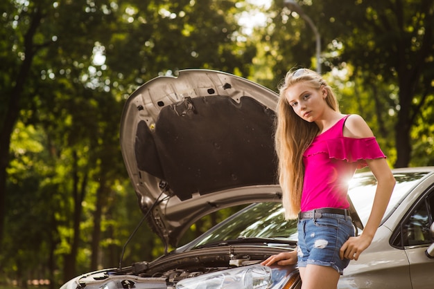 Foto nadenkend vrouw in de buurt van gebroken auto