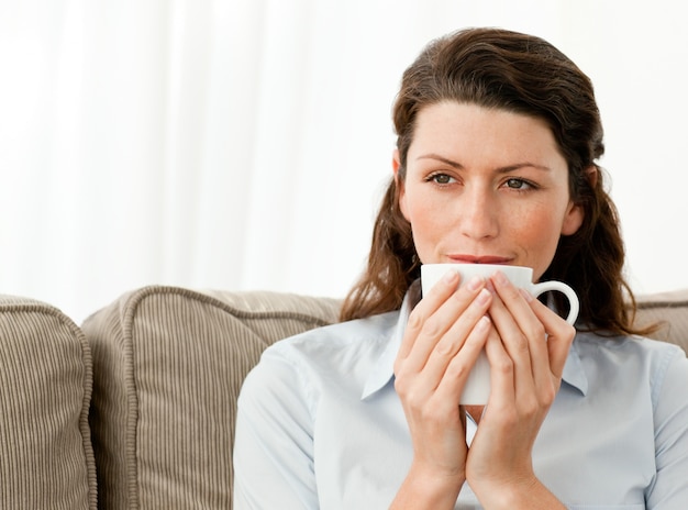 Nadenkend vrouw koffie drinken in de woonkamer