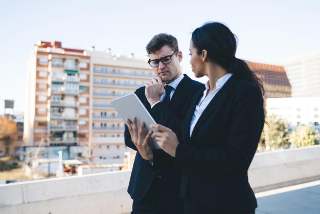 Nadenkend zakenman kijken naar tablet met collega