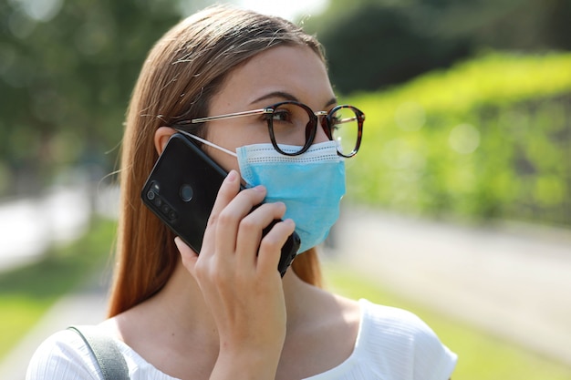 Nadenkend zakenvrouw praten over slimme telefoon met behulp van chirurgische masker coronavirus vermijden in de straat van de stad