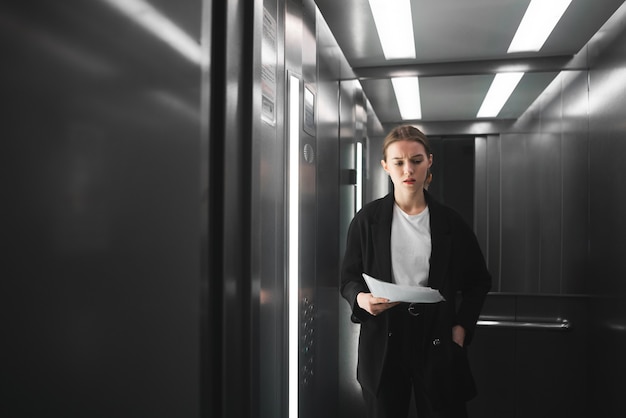 Nadenkende ambitieuze zakenvrouw staat in de lift en probeert zich iets te herinneren.