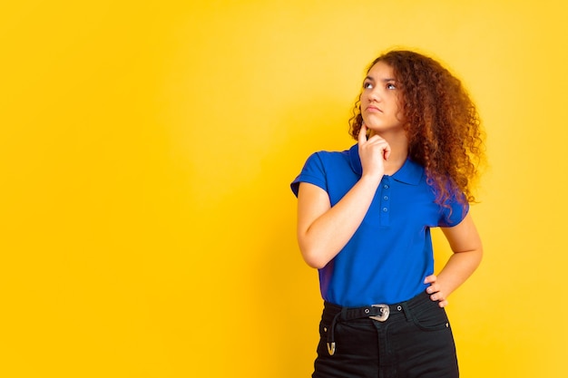 Nadenkende jonge vrouw met blauw poloshirt en blauwe broek