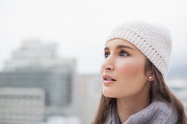 Nadenkende leuke vrouw met de winterkleren bij het stellen