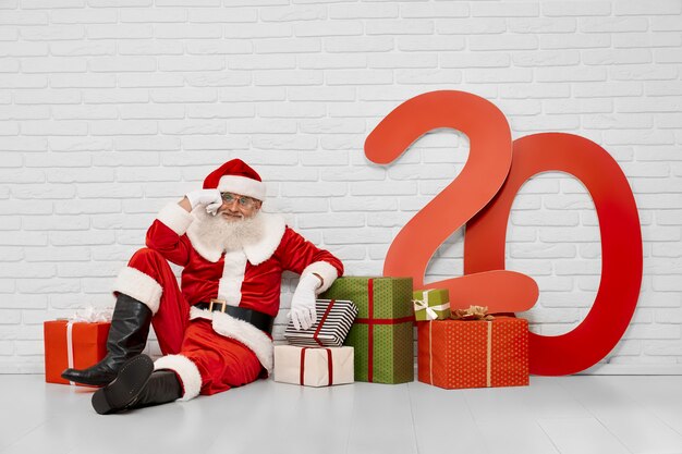 Nadenkende Santa Claus-zitting op vloer met giftdozen