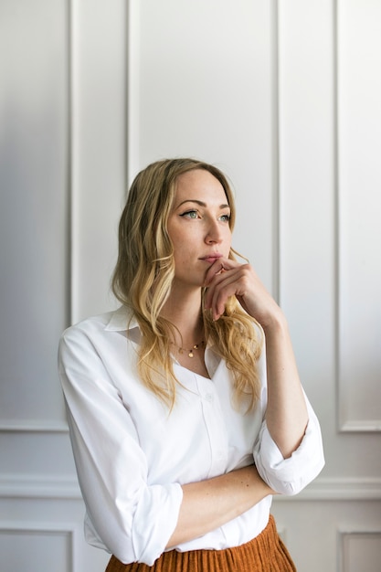 Nadenkende vrouw bij een witte muur