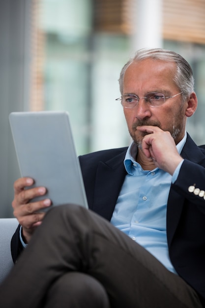 Nadenkende zakenman die een digitale tablet houdt