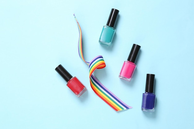 Nagellakflessen en LGBT Rainbow Ribbon Pride Tape-symbool op blauwe achtergrond Bovenaanzicht
