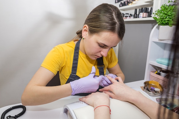 Nagelriemverwijdering met een nagelschaartje. De meester maakt een manicure voor de klant in de salon.