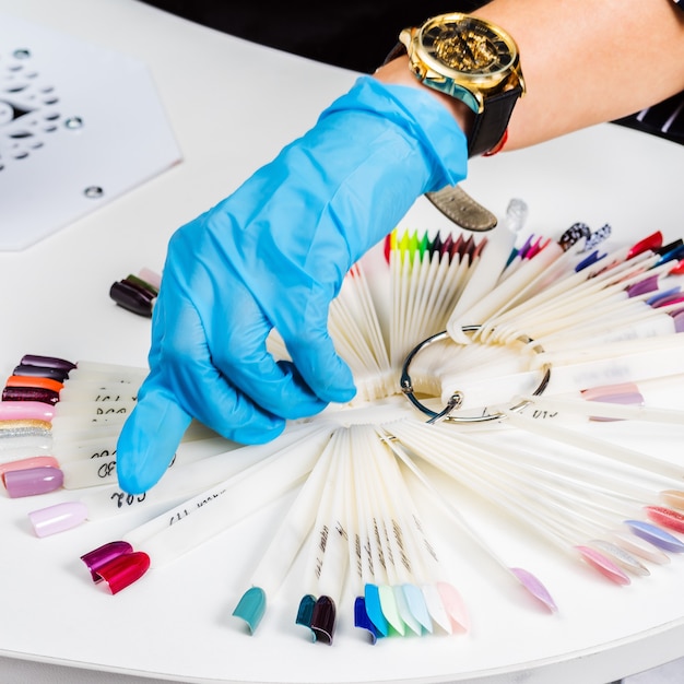 Foto nagelsalon meesters hand close-up toont opties voor gekleurde nagellak