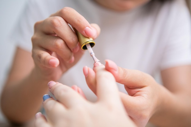 Cura delle unghie e manicure. primo piano di belle mani femminili che applicano lo smalto sulle unghie sane