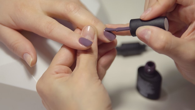 Nail care in the salon. Master applies gel-lacquer on the nails of a young woman.