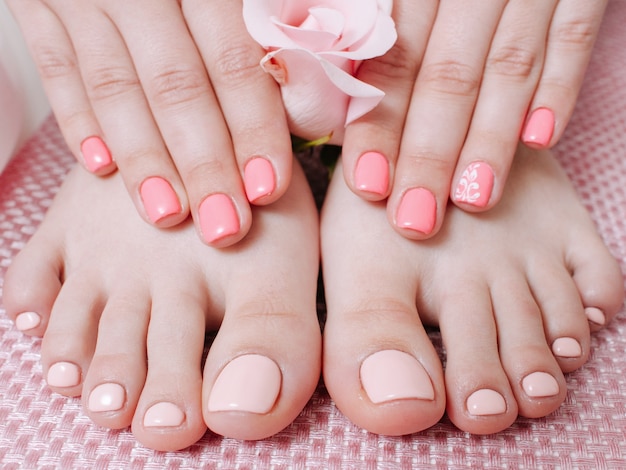 Nail care service. Skin therapy. Manicure pedicure. Female hands feet. Pastel peach polish.