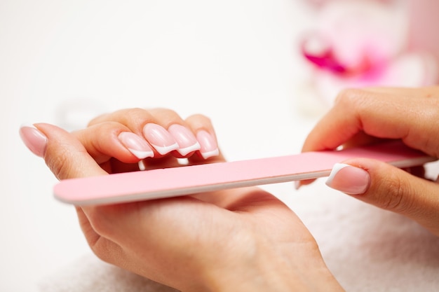 Foto cura delle unghie, donna con belle mani facendo manicure in studio di bellezza