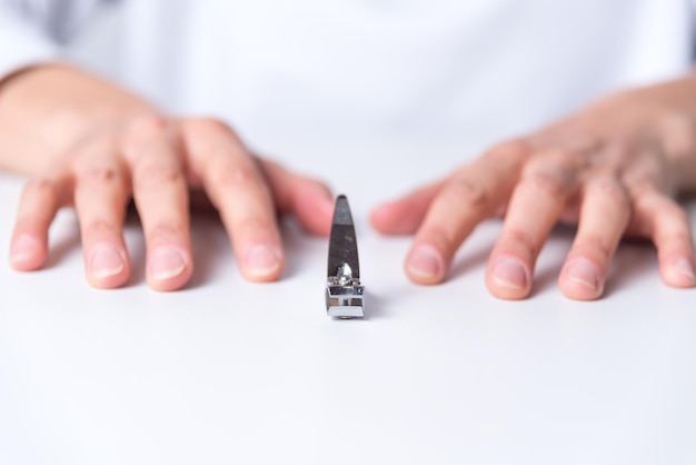 A nail clipper between woman's hands neutral background body health and beauty