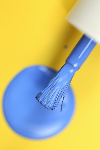 Nail polish blue drops of nail polish and brush on bright yellow background