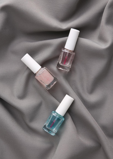 Nail polish bottles on a gray silk background Beauty concept