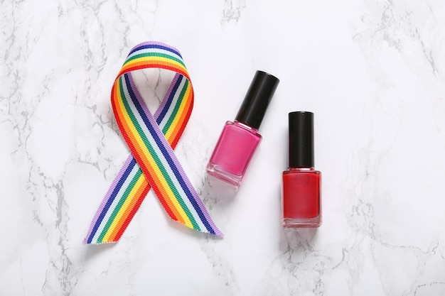 Nail polish bottles and lgbt rainbow tape on marble background