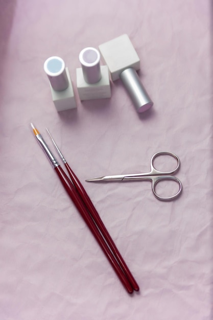 Nail salon table with manicure tools and nail polish bottles on
pink background flat lay top view beauty treatment concept