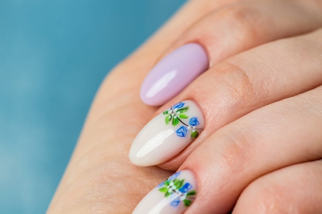 Nails Design. Hands With Bright lilac and White Manicure with Spring flowers. Close Up Of Female Hands. Art Nail.