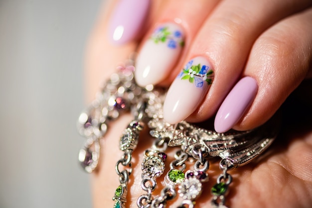 Nails Design. Hands With Bright lilac and White Manicure with Spring flowers. Close Up Of Female Hands. Art Nail.