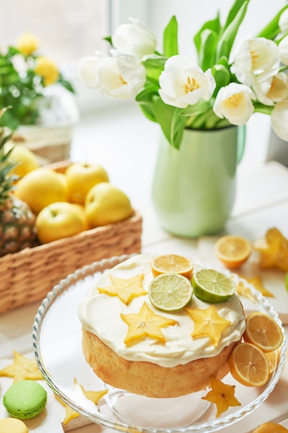 Naked cake with lemons and limes, fruits and white tulips