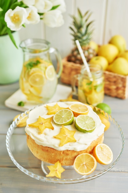 Foto torta nuda con limoni e lime, limonata, frutta e fiori di tulipano