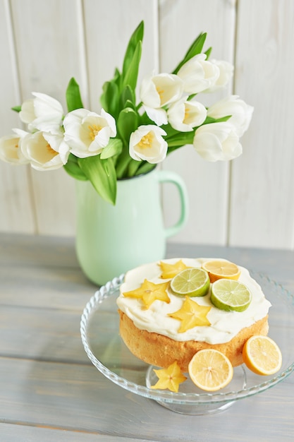 Foto torta nuda con limoni e lime e fiori di tulipano