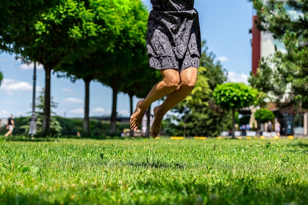 写真 公園の緑を背景に裸足でジャンプするつま先で裸の女性の足