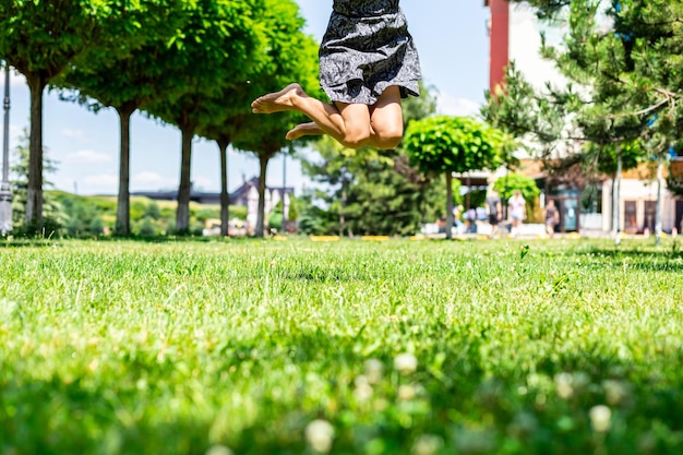 公園の緑を背景に裸足でジャンプするつま先で裸の女性の足