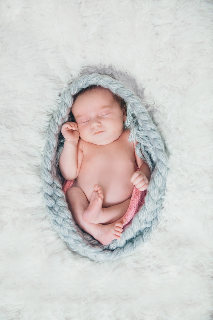 Photo naked newborn baby sleeps curled up in a ball in a braided rope