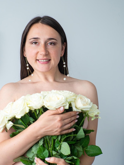 Naked woman covering her body with large bouquet of roses