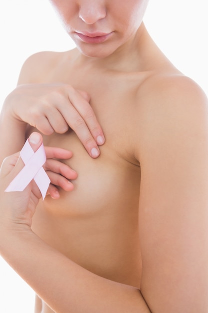 Naked woman holding breast cancer ribbon