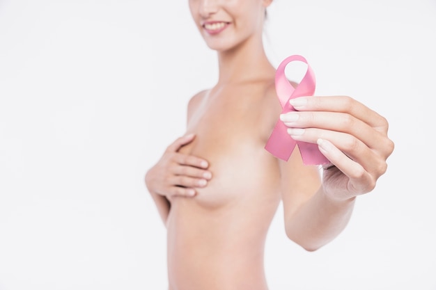 Naked woman holding pink awareness ribbon