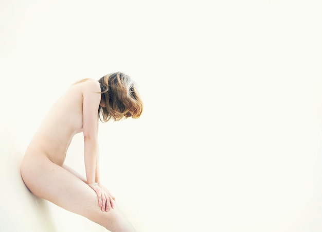 白い背景に傾いた裸の女性