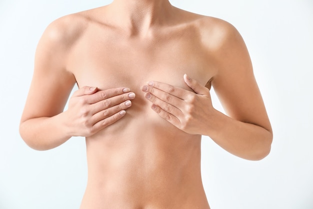 Naked woman on light background. Concept of breast augmentation