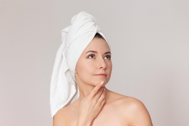 naked woman looks up thoughtfully touching her chin with her finger Isolated on a light background