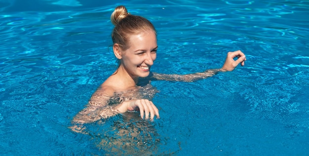 Naked woman outdoors. Beautiful young nude woman in swimming pool. Young nude blonde swims in the outdoor pool