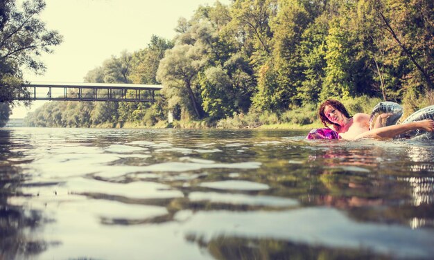 Photo naked woman with inflatable balloons swimming in river at forest