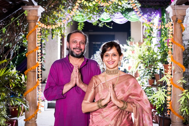 Фото Намасте или намаскара - индийская пара, приветствующая гостей на фестивале дивали или свадьбе.