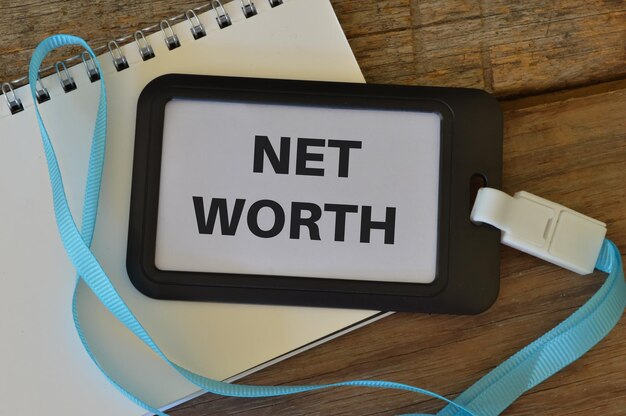 木製の背景にテキスト NET WORTH で書かれた名札