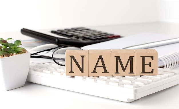 Nome scritto su un cubo di legno sulla tastiera con strumenti da ufficio