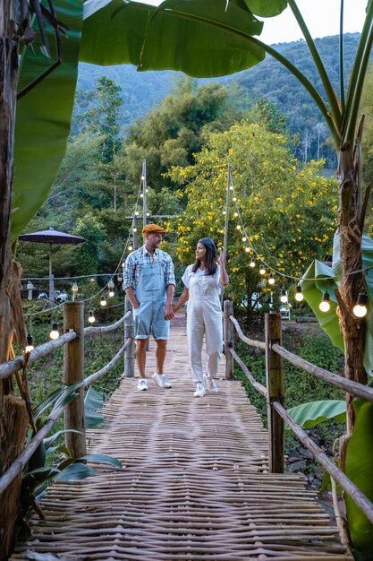 Foto montagne nan della valle di sapan in thailandia con campi di riso e foresta coppia uomo e donna che camminano sul ponte di bambù di legno sul fiume a bo klue