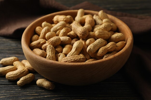 Napkin and bowl with peanut on wooden background